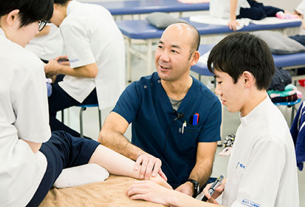 実習中の学生と説明をする講師
